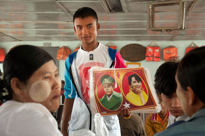 A young man holding a photograph of Opposition leader Aung San Suu Kyi and her father, General Aung San. Yangon Ferry, 2012. Image Credit: Geoffrey Hiller.