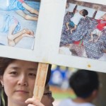 A woman holds up a poster with photos fr