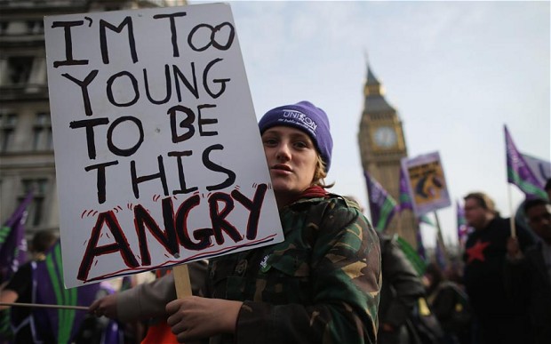 A protestor holds up a banner reading 'I'm too young to be this Angry' while taking part in a TUC march in protest in London Photo: GETTY